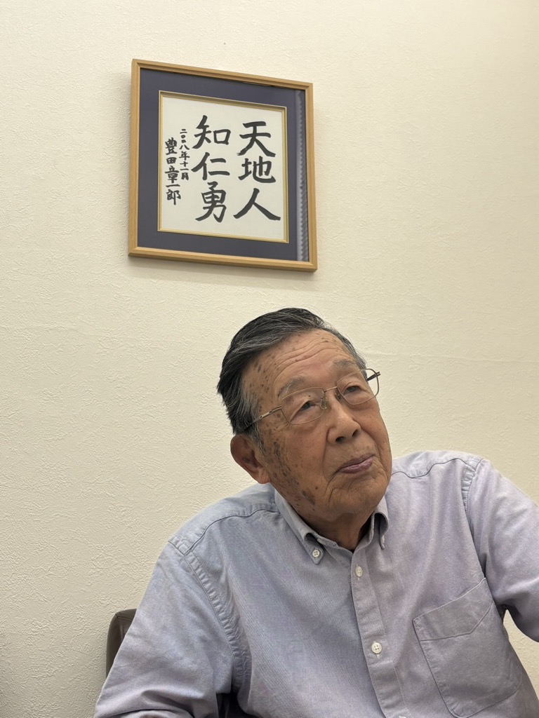 豊田章一郎さんが記した言葉の前で語る菅沼さん